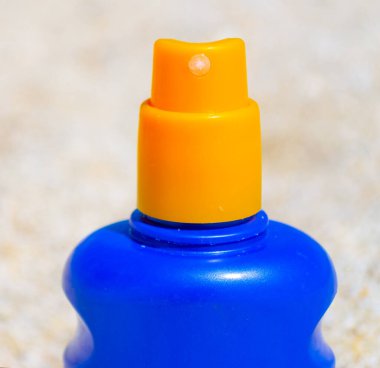 Beyaz bir plajda mavi ve sarı bir güneş şişesine aşırı yakın çekim