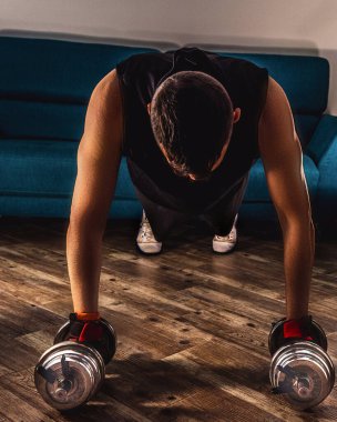 Ev çalışması sırasında dambıllarla tahta yapan bir adam.