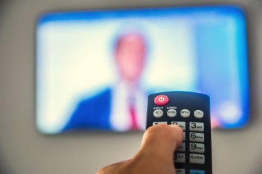 Otel odasında televizyon izleyen bir adam.