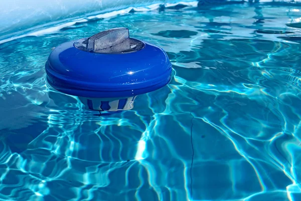 晴れた日にプールに浮かぶ青い塩素ディスペンサー 塩素ディスペンサーは スイミングプールの水を消毒するために使用されます — ストック写真