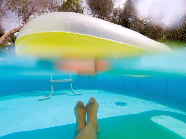 浮遊空気マットレスの下でプールでリラックスした男の水中ポフを分割 — ストック写真
