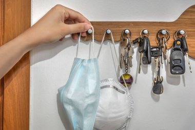 Bir kadının eli dışarı çıkmadan önce virüs koruyucu bir maske alıyor.