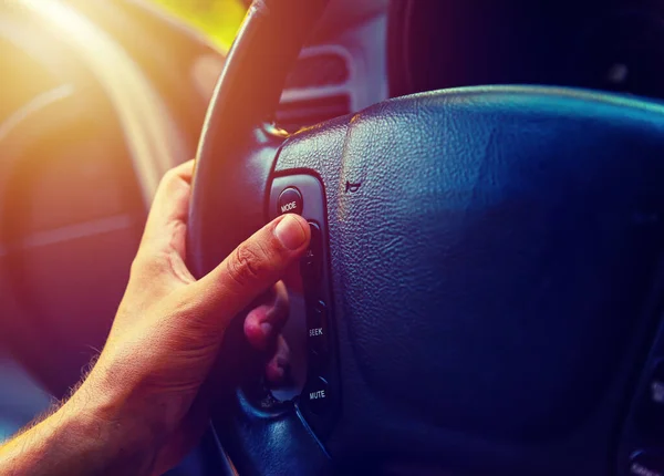 Close up of a man setting stereo volume by pressing a button on steering wheel control