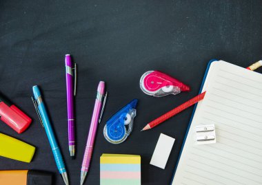 Yukarıdan görülen karatahtanın üzerindeki kalemler ve diğer okul nesneleri