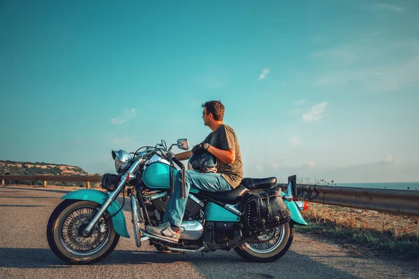 Gün batımında klasik bir motorsikletle deniz kenarında.
