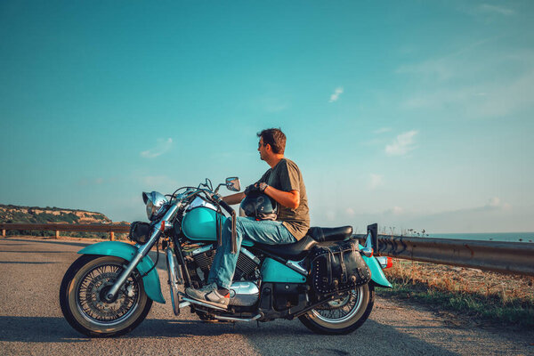 Biker on a classic motorcycle by the sea at sunset