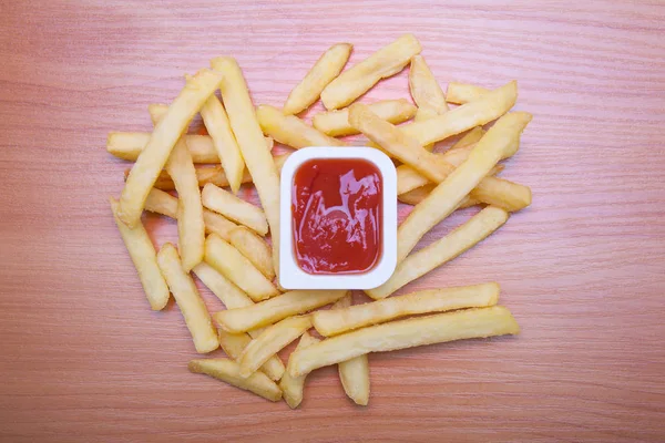 Frites et sauce rouge isolées sur le bois — Photo