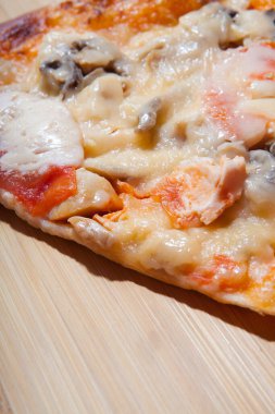 Kesme tahtasında mantar ve domatesli bir dilim pizza. Kapat.