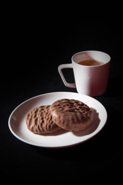 Küçük atıştırmalıklar Kurabiyeler ve çay siyah arkaplanda izole edilmiş.