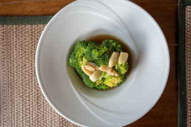 Sarımsaklı kızarmış brokoli içinde güzel beyaz yuvarlak tabak istiridye sosu ilave edin.