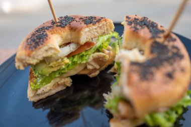 Begel siyah susam Tavuk salatası ile siyah plaka üstüne sopayla ikiye böldüm.