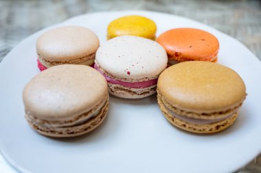 Beyaz yuvarlak plaka üzerinde çeşitli tadında renkli acıbadem kurabiyesi.