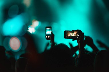 Akıllı telefonlarını veya cep telefonlarını tutan ve fotoğraf konseri yapan kişiler