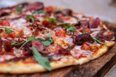 Biftek dilimli pizza, domates sosu ve biraz yeşillik. Pizza tahtanın üzerinde. Görüntüyü kapat 