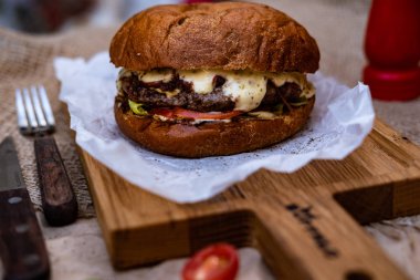 Büyük bir sığır pirzolası, beyaz biber sosu, bir dilim domates ve peynir ile lezzetli bir burger. 