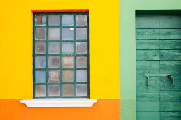 Yellow wall and green wooden door in Burano island, Venice, Italy