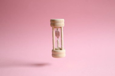 Pembe arka plan üzerinde yüzen kum saati. İş son tarih, son saniye veya zaman aşımına kavramı