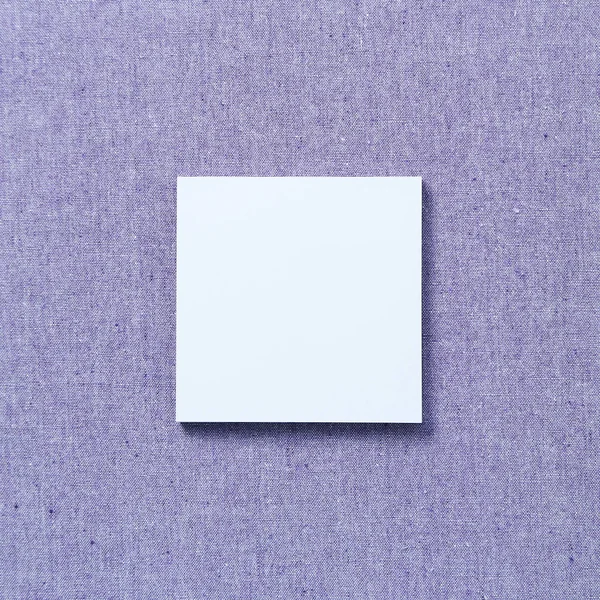 Blue memo pad, sticky note on purple fabric texture background