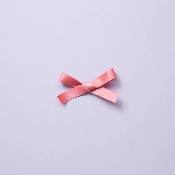 Wstążki dekoracyjne różową kokardką na fioletowym tle — Zdjęcie stockowe