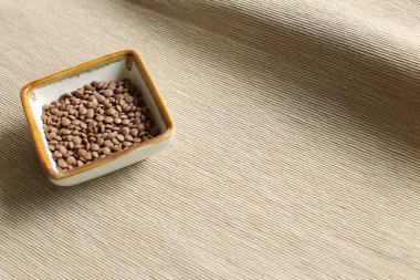 Sağlıklı yiyecek bej kumaş arka planında bir kasede mercimek