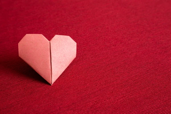 Red paper heart origami on red fabric background. copy space