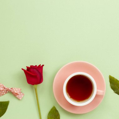 Yeşil arka planda kırmızı gül olan bir fincan siyah çay. Düz konum, üst görünüm, kopyalama alanı