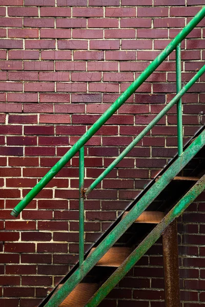 Rusty green iron stairs with brown brick wall background