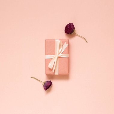 Pembe arka planda kuru ranunculus çiçeği olan pembe hediye kutusu. Üst görünüm, boşluk kopyala