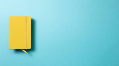Mavi arka planda sarı günlük defteri. Üst görünüm, boşluk kopyala