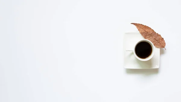 Cup of coffee with leaves on white background. top view