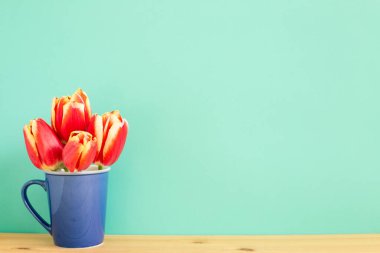 Nane yeşili arkaplanlı ahşap masada kırmızı lale çiçekleri. Çiçek aranjmanı, kopyalama alanı