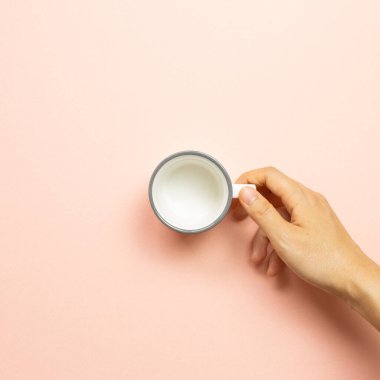 Pembe arka planda beyaz boş bardak tutan bir kadın. en üstteki görünüm