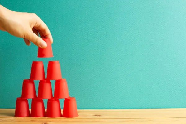 Pirâmide Copos Plástico Vermelho Mesa Madeira Com Fundo Verde — Fotografia de Stock