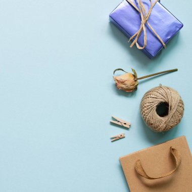 Hediye kutusu, ip, mavi arka planda kuru gül çiçekli alışveriş çantası. düz alan, üst görünüm, kopyala boşluk