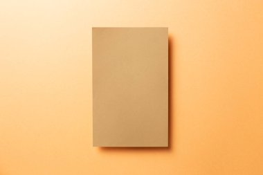 Kraft kahverengi not defteri, turuncu arka planda boş kağıt. Üst görünüm, boşluk kopyala