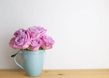 İç mekan. Ahşap masada beyaz arkaplanlı bir demet mor gül çiçeği. Çiçek aranjmanı, kopyalama alanı