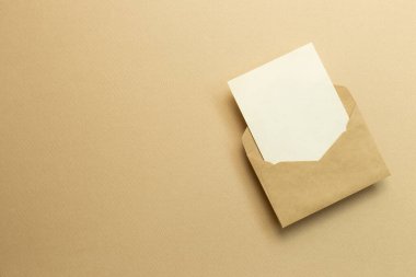 Bej arka planda, Kraft zarfında boş bir kart. Üst görünüm, boşluk kopyala