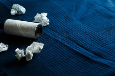 Karanlık bir ekose ve bir silindir yapışkan bant ile yün elbise temizliği için hafif yün sıkışmış.