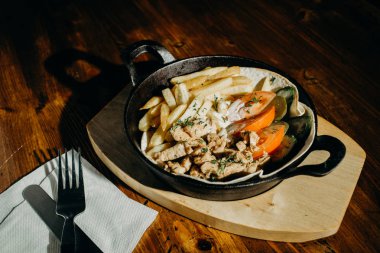 kızarmış patates, kızarmış tavuk ve Sebze soslu bir tavada bir çatal ve bıçak ile yapılabilir