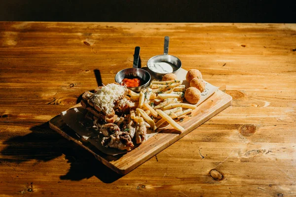 Variety of fatty foods and beer snacks on a wooden table.