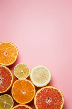 bir bardak taze lezzetli suyu yanında bir tepsi üzerinde pembe bir arka plan üzerinde yarım sulu turuncu kesilmiş