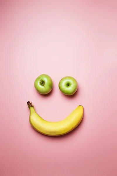 Банан и яблоки улыбаются на розовом фоне моды с пространством для текста — стоковое фото