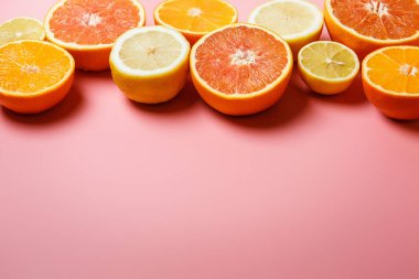 Güzel portakal, limon, mandalina ve diğer turuncu kopya alanı hoş bir pembe zemin üzerine dilimlenmiş. Narenciye çerçeve metin için
