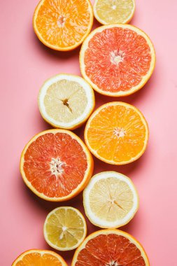 Güzel portakal, limon, mandalina ve diğer turuncu kopya alanı hoş bir pembe zemin üzerine dilimlenmiş. Narenciye çerçeve metin için