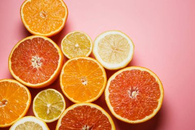 Güzel portakal, limon, mandalina ve diğer turuncu kopya alanı hoş bir pembe zemin üzerine dilimlenmiş. Narenciye çerçeve metin için