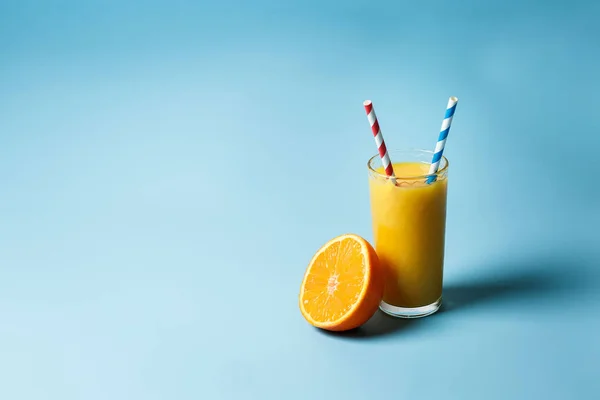bir bardak taze juce ve bir limon ve portakal kopya alanı ile mavi bir arka plan üzerinde yanında iki kağıt tüp