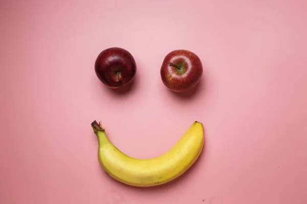 Улыбающееся Лицо Двумя Яблоками Бананом Копировальным Местом Розовом Фоне — стоковое фото