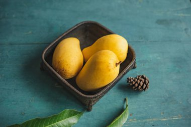 Yeşil bir ahşap üzerinde bir sepet içinde Mango