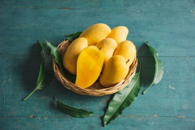 Yeşil bir ahşap üzerinde bir sepet içinde Mango