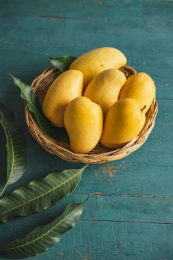 Yeşil bir ahşap üzerinde bir sepet içinde Mango